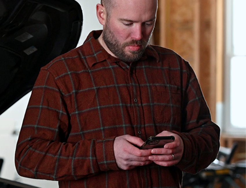 A technician checking the Repair Club app on a phone in the shop